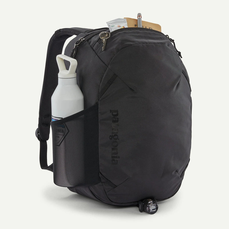 Load image into Gallery viewer, Black backpack with a water bottle and small items on a white background
