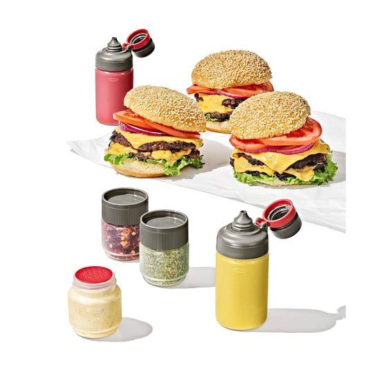 Three burgers with various condiments and a set of small containers on a white background