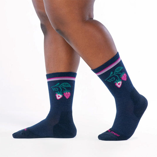 Navy socks with green leaves and pink berries design worn by a person on a white background
