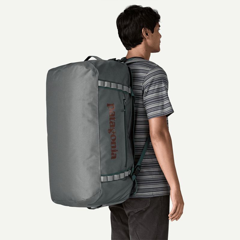 Load image into Gallery viewer, Person wearing a large gray backpack with Patagonia logo on a white background
